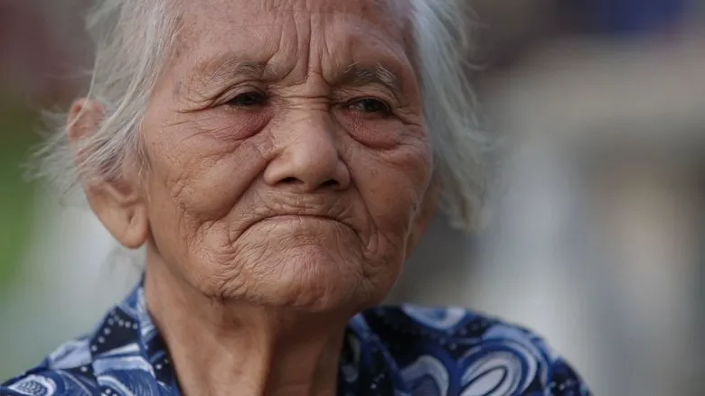 An intimate scene with Mbah Sri interacting with a young boy, perhaps her companion on the journey