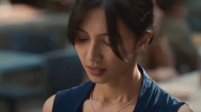 A woman looking directly at the camera, with a serious and unwavering expression.