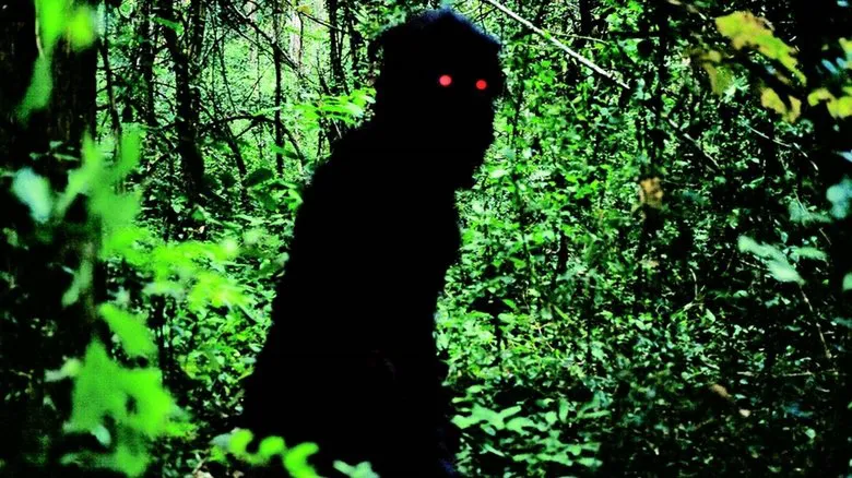 Uncle Boonmee conversing with the translucent ghost of his wife at a table, highlighting the film's unique depiction of past lives.